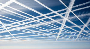Varios aviones dejando estelas químicas (chemtrails) que forman un patrón de cuadrícula en un cielo azul, sugiriendo una operación coordinada de fumigación.