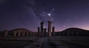 Los pilares en forma de T de Gobekli Tepe al atardecer, con la constelación de Orión brillando en el cielo directamente sobre ellos, simbolizando su propósito astronómico.